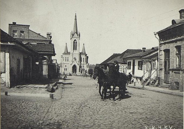 Забрукована вулиця Кафедральна. Видно, що проїзну частину відділили від тротуарів підвищенням. Біля цього підвищення виникає канавка для стікання води. Фото з Австрійської національної бібліотеки